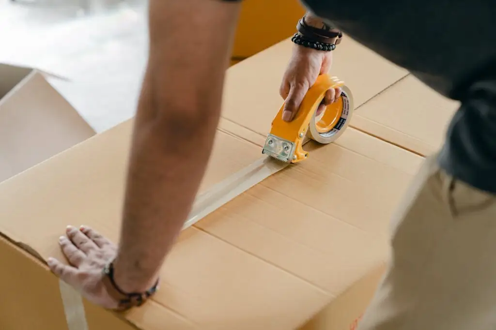 Friendly local movers in Sacramento carrying securely packed boxes out of a residential home